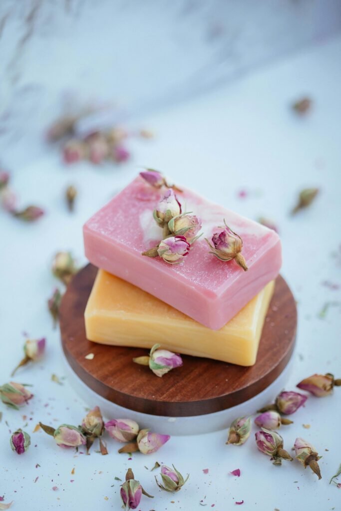 Pink and yellow soap bars with dried roses, perfect for skincare and spa aesthetics.